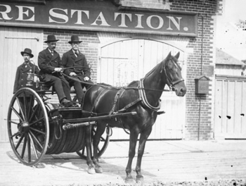 Horse-drawn Hose Reel with 500 feet of hose wrapped around the axle in front of No. 2 Fire Station, 123 Lyon Street at Queen Street, 1880 Left to right: Richard Waggoner, Hugh Latimer, and Thomas Stanford